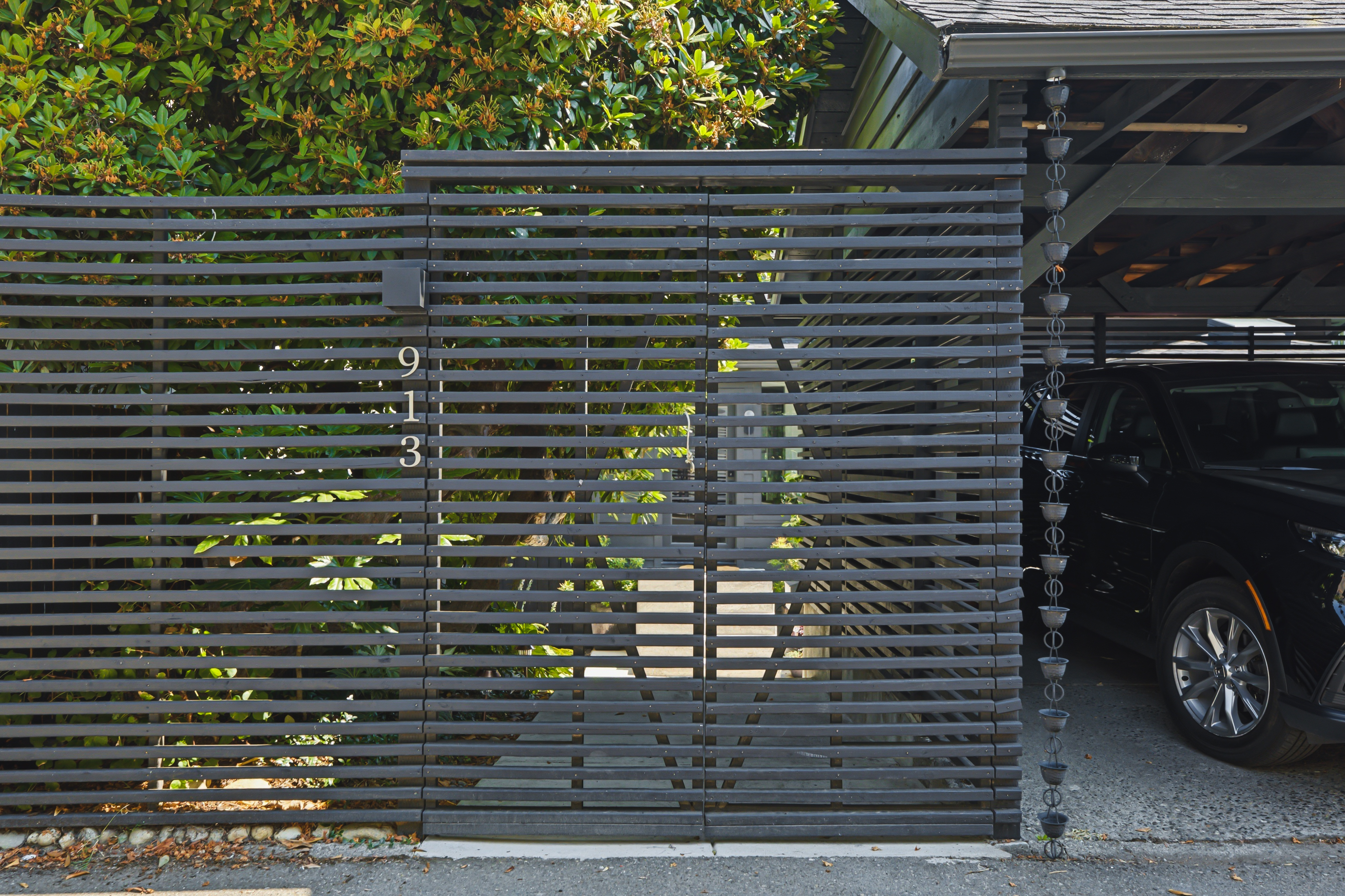 Cedar slat gate with the house number and the carport beyond