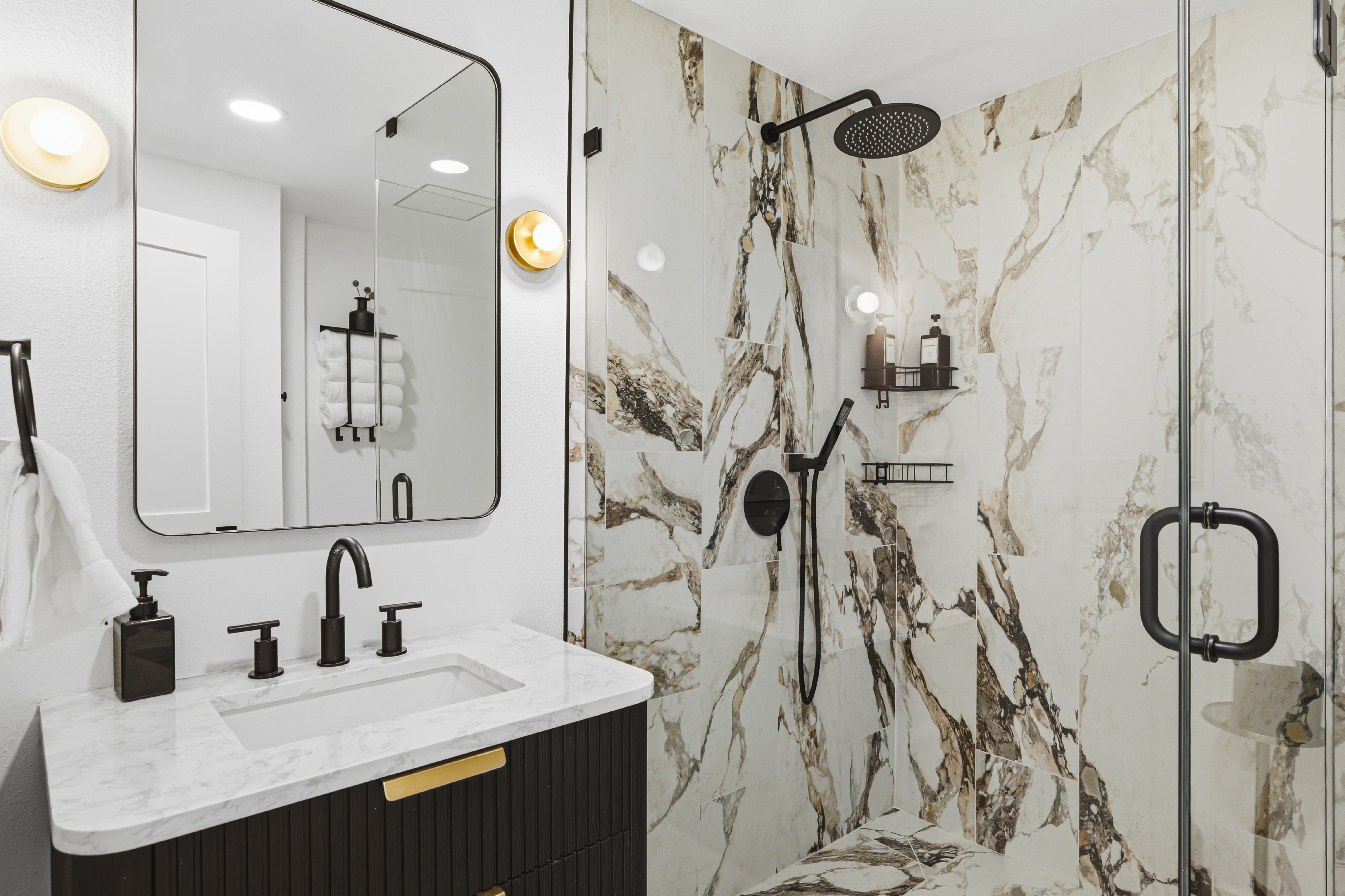 Marble bathroom with a fluted black vanity and a walk in shower