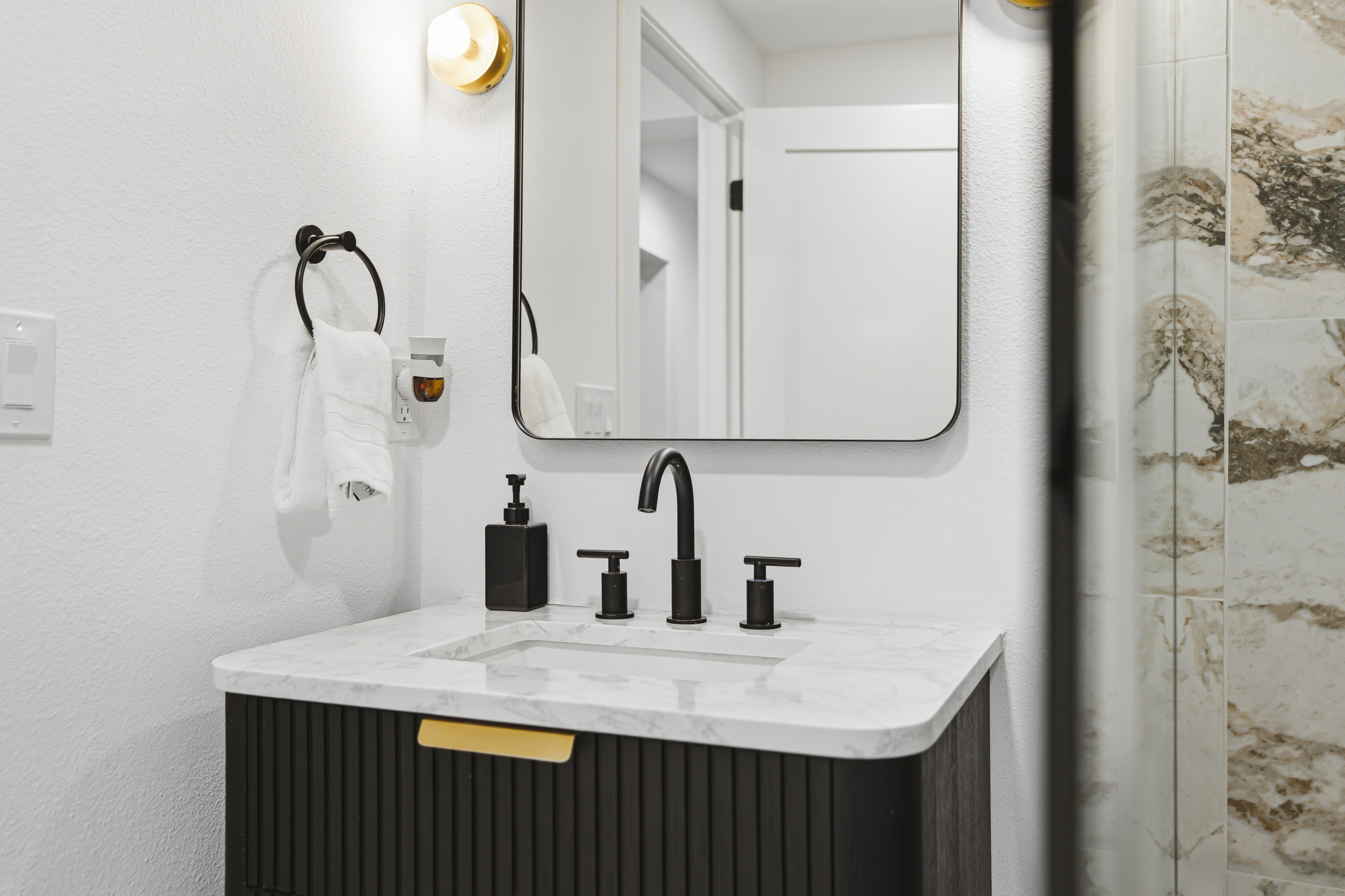 Vanity with a black tap and a soft edged mirror