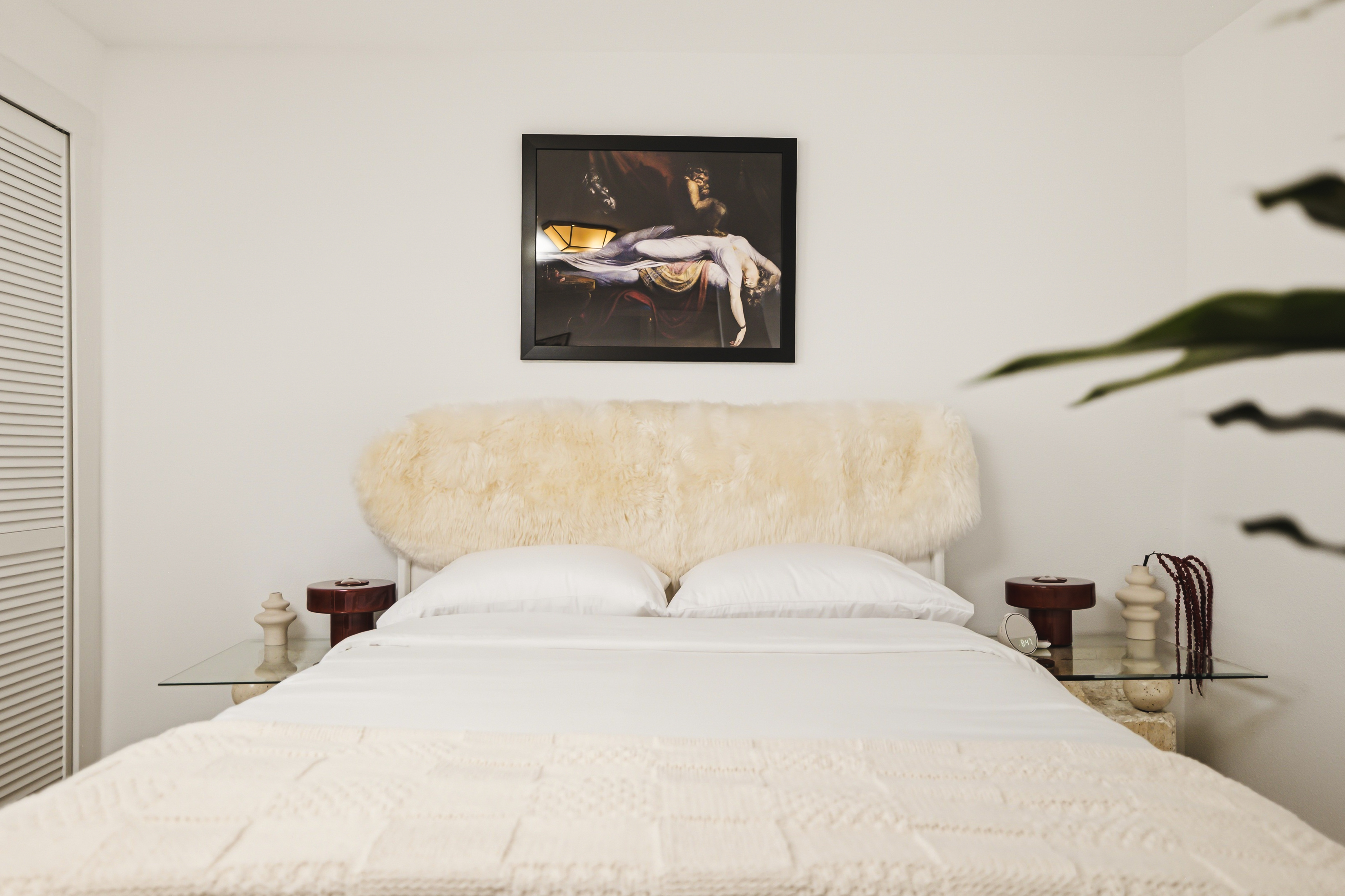 Bedroom with a pale sheepskin headboard and white down bedding