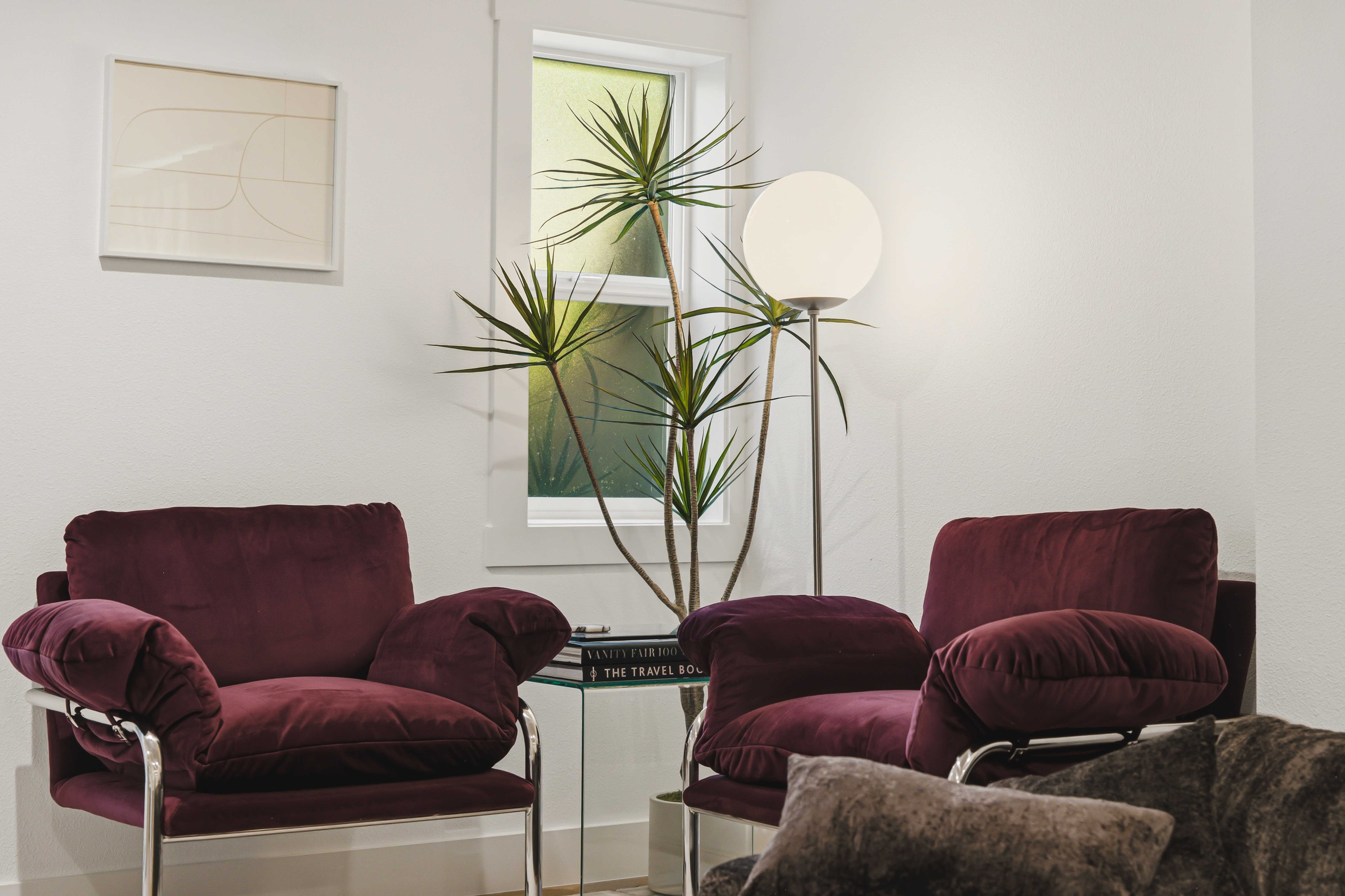 Two velvet armchairs around a glass table with a floor lamp