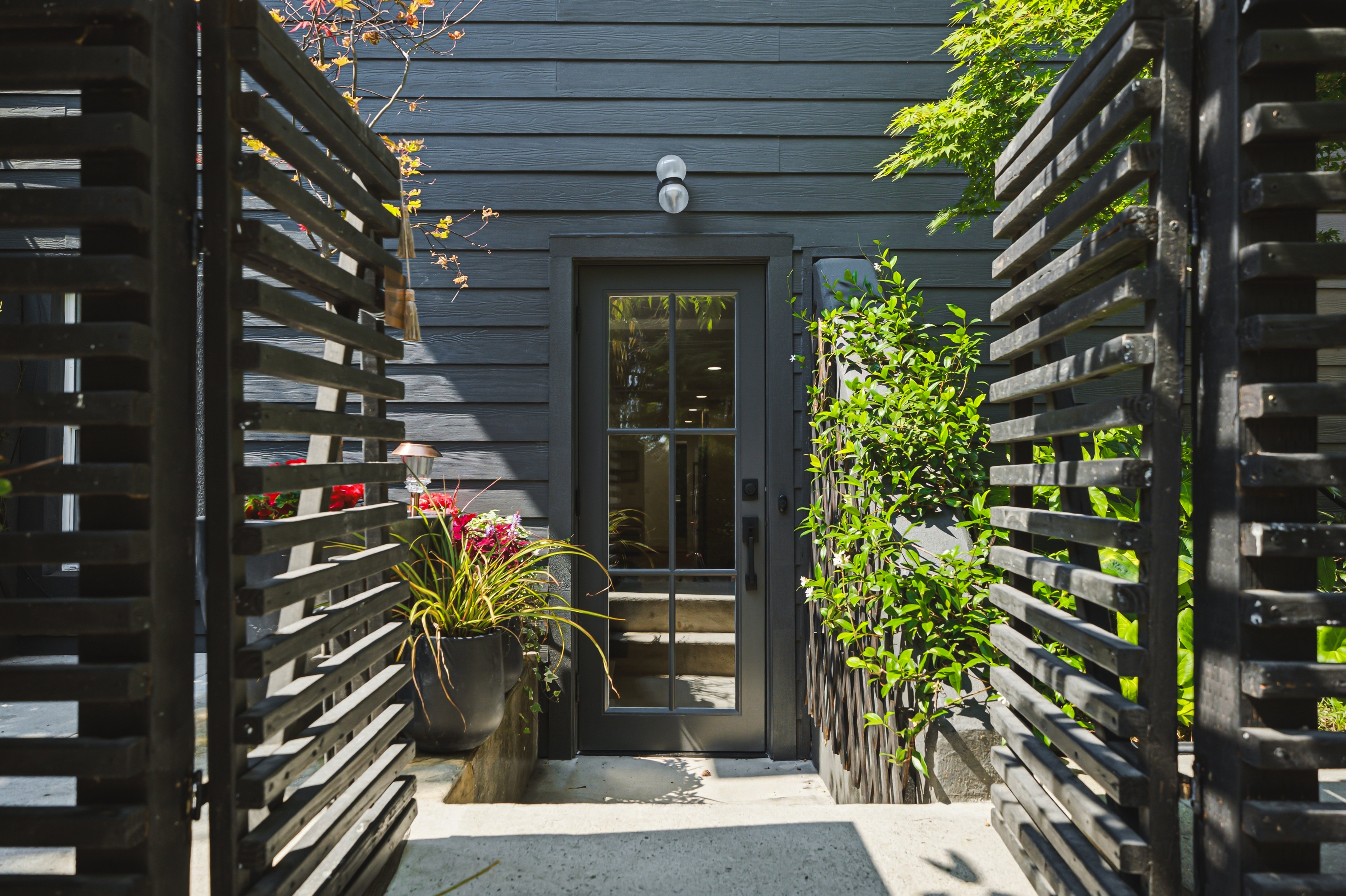 Private entrance framed by cedar screens, planters and climbing jasmine