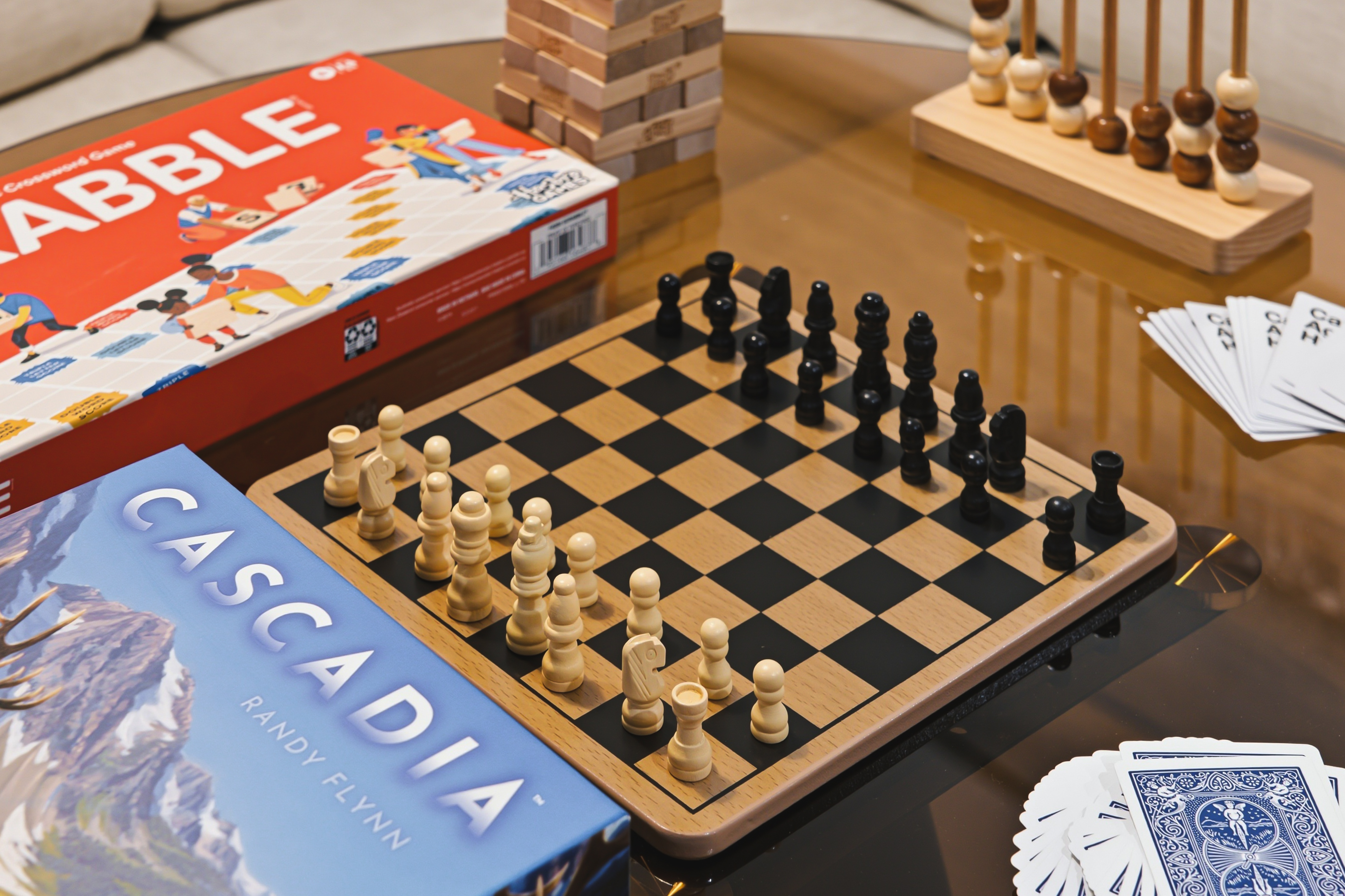 Board games and cards laid out on the table, including chess and Cascadia