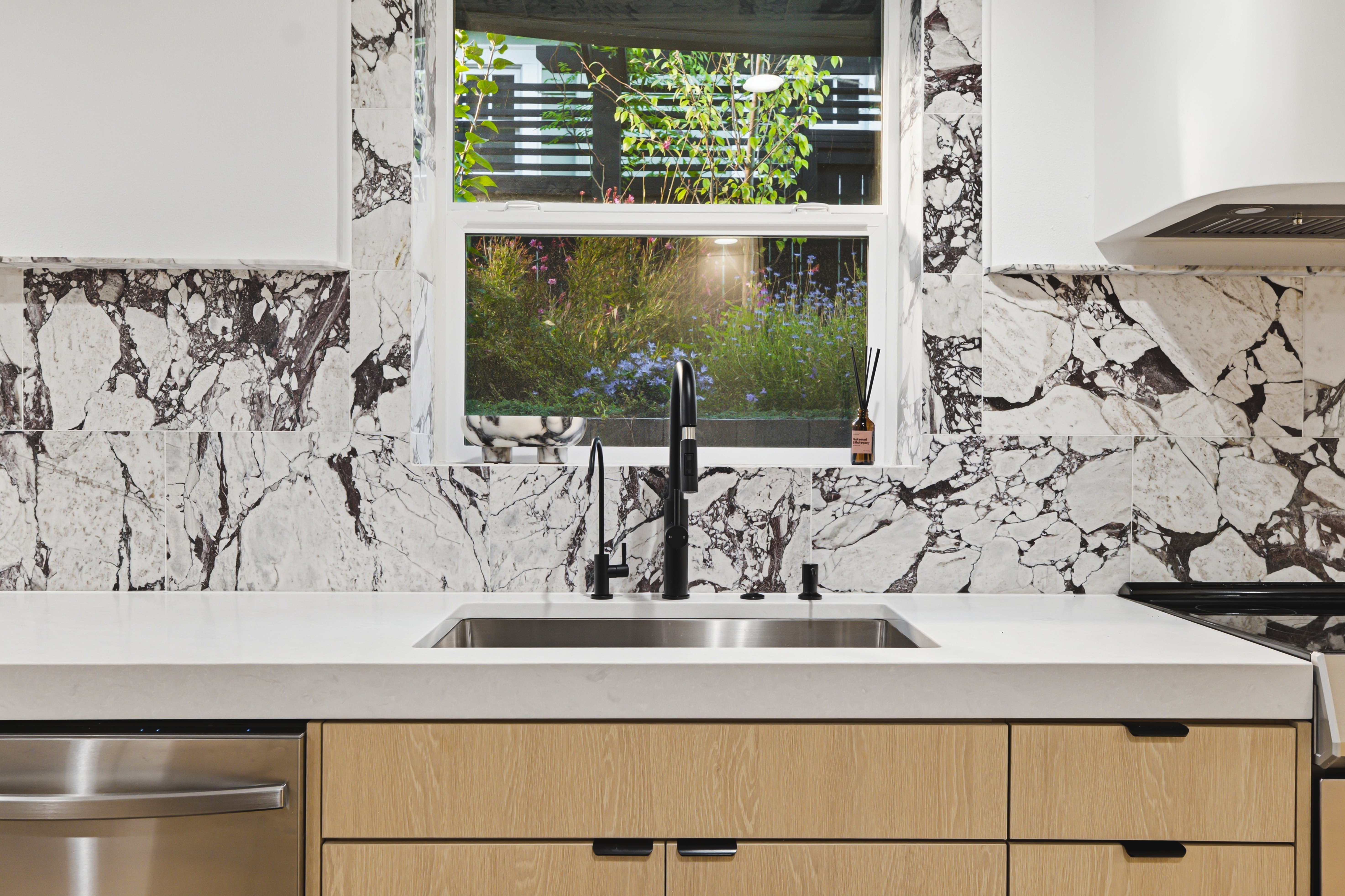 Calacatta Viola marble kitchen with a window over the sink looking into the garden