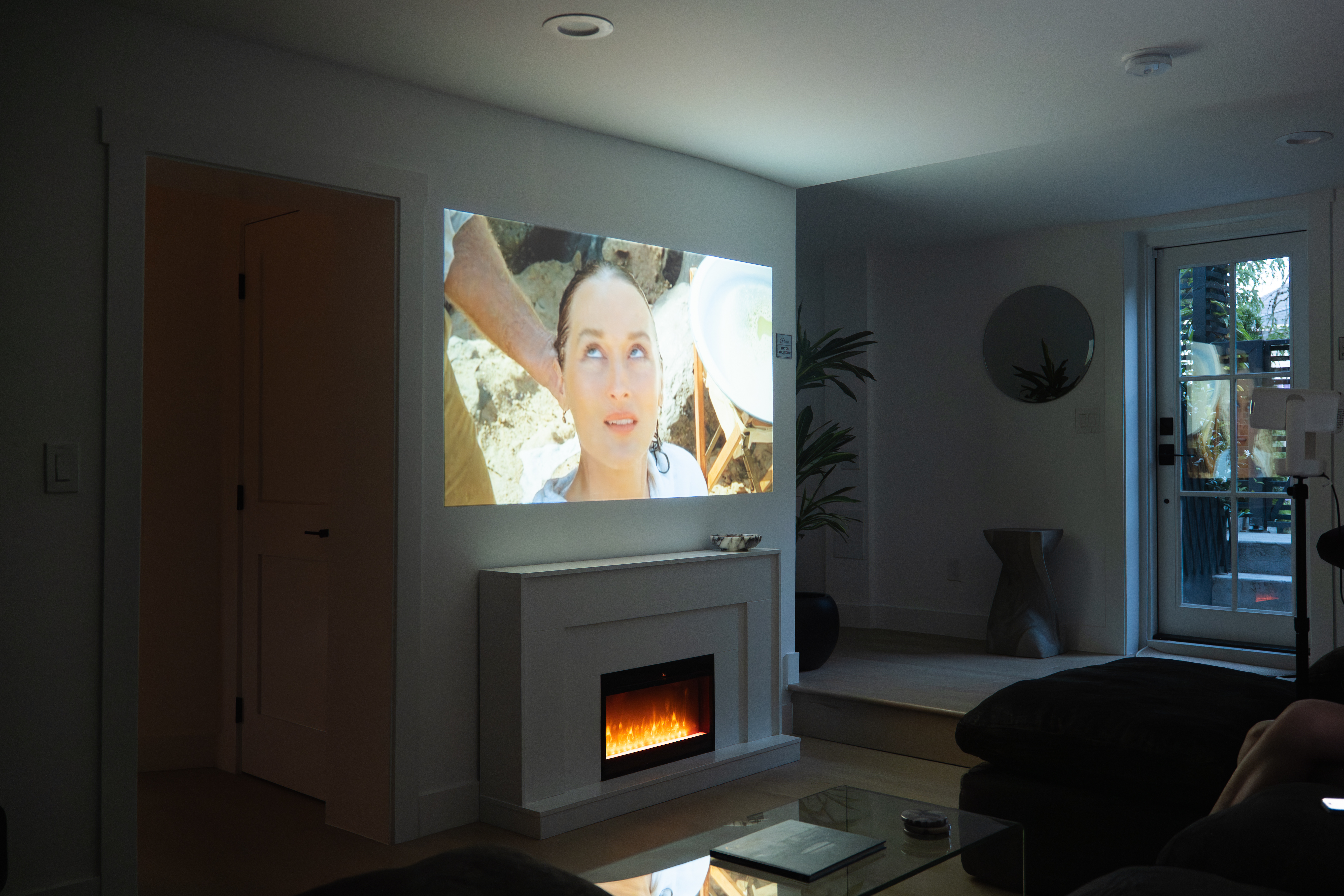 Film projected onto the living room wall above the fireplace at night