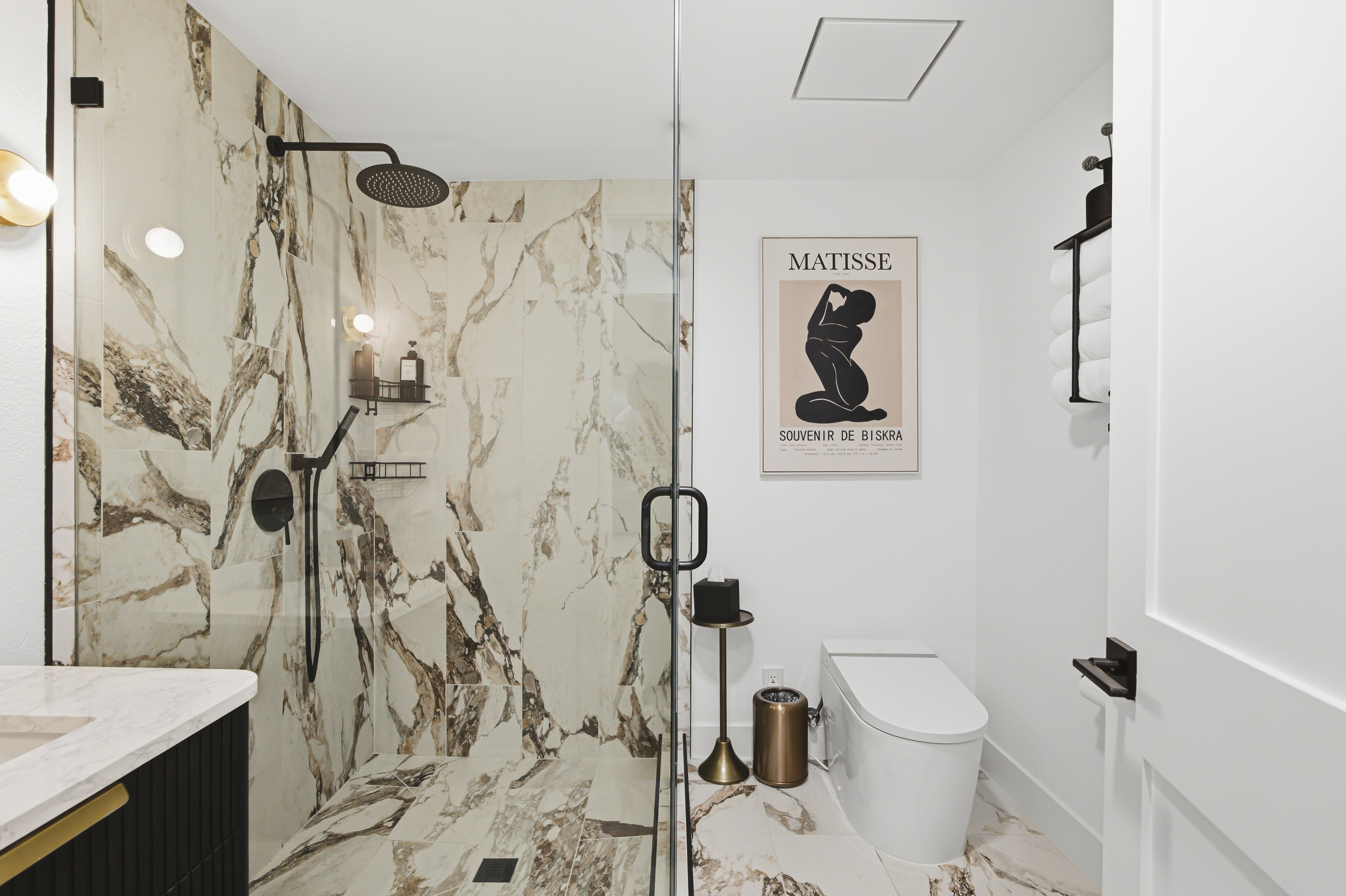 Marble walk in shower with a glass panel and black fittings